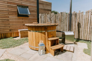 A wood-fired hot tub outside a private wooden cabin at The Meadows at Polehanger, a beautiful glamping location in the UK.