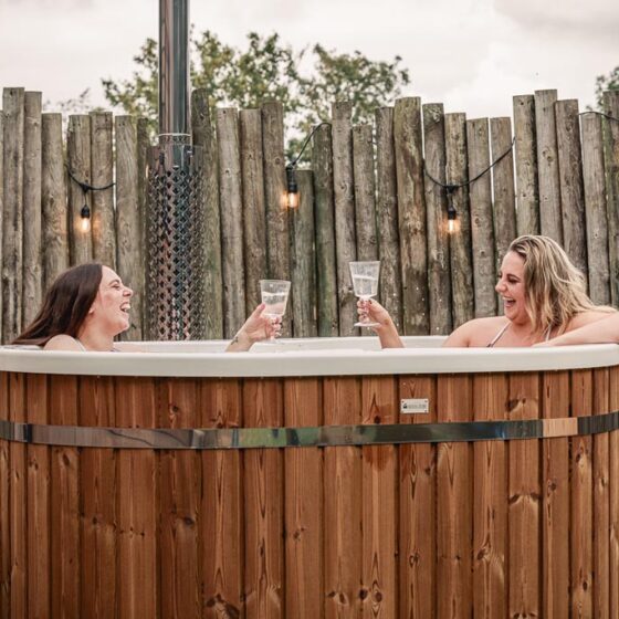 Friends enjoying a drink in the Aster cabin wood-fired hot tub