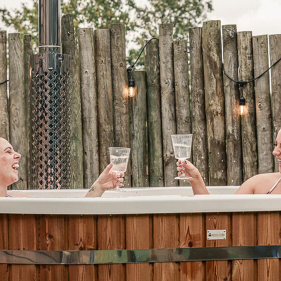 Friends enjoying a drink in the Aster cabin wood-fired hot tub