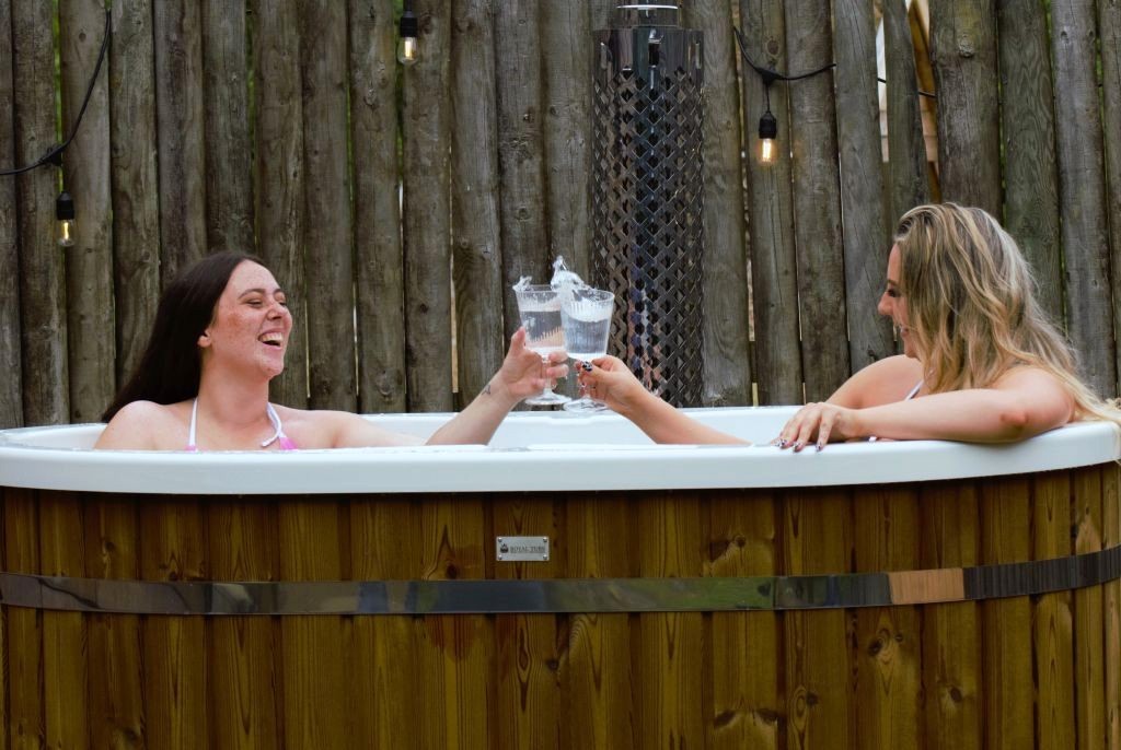 Friends relaxing in a wood-fired hot tub during a luxury glamping hen weekend